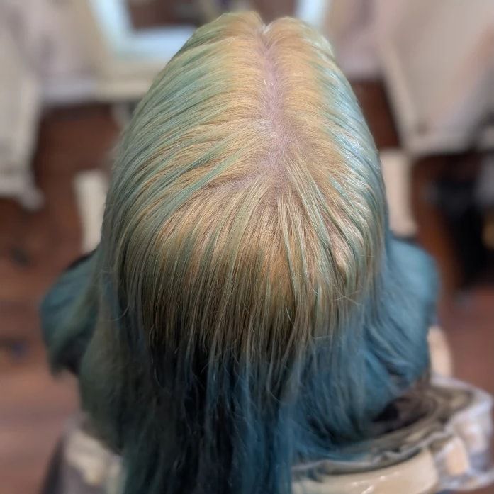 Top of the head before the correction: a yellow-green cast at the roots fading into teal lengths