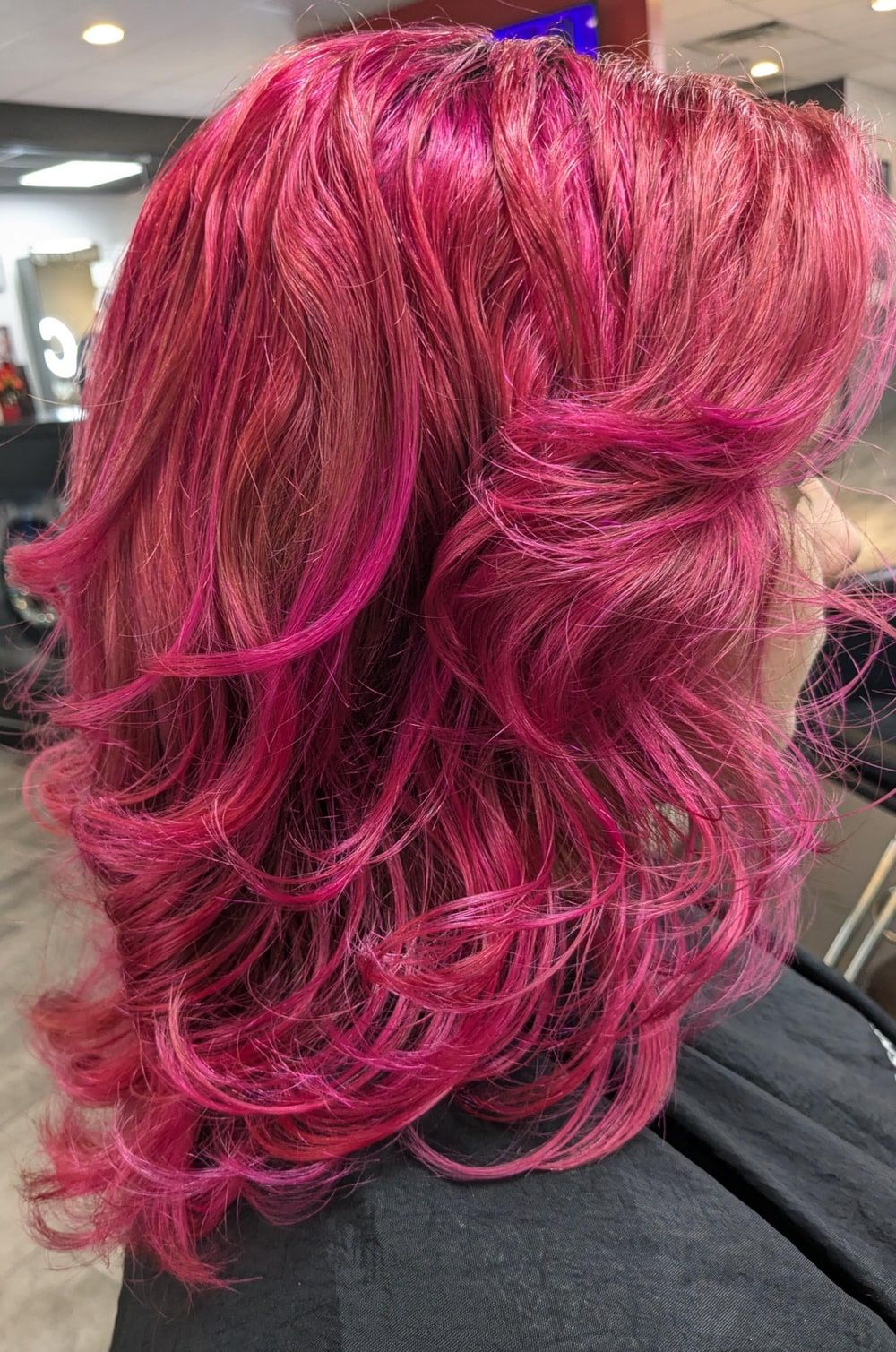 Layered hair styled in soft, bouncy curls on a real client