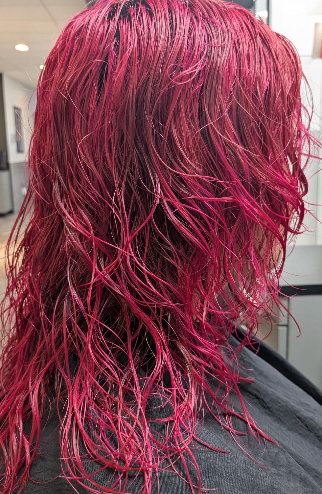 Magenta color just applied to wet hair, photographed from the back in the salon